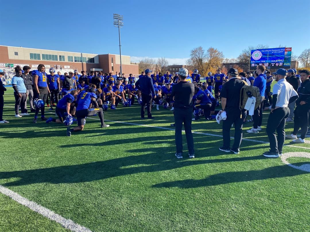 UNK's football team huddles after its final game of the 2024 season.